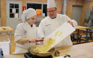 Culinary student and instructor work together while cooking