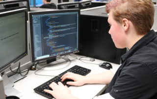 Information Technology student practices coding on his computer