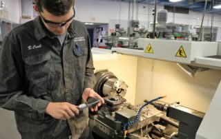 Precision Machining student examines tool while working in the shop