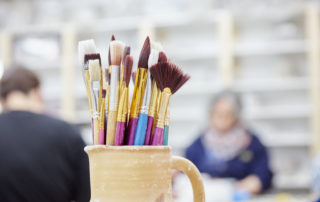Close up of a pottery jug with paintbrushes.