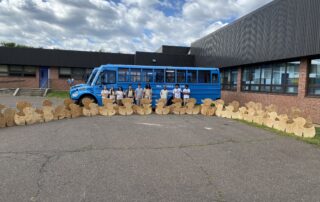 Vinal Tech Carpentry students standing in front of the blue production bus with their cut-outs of ducks.