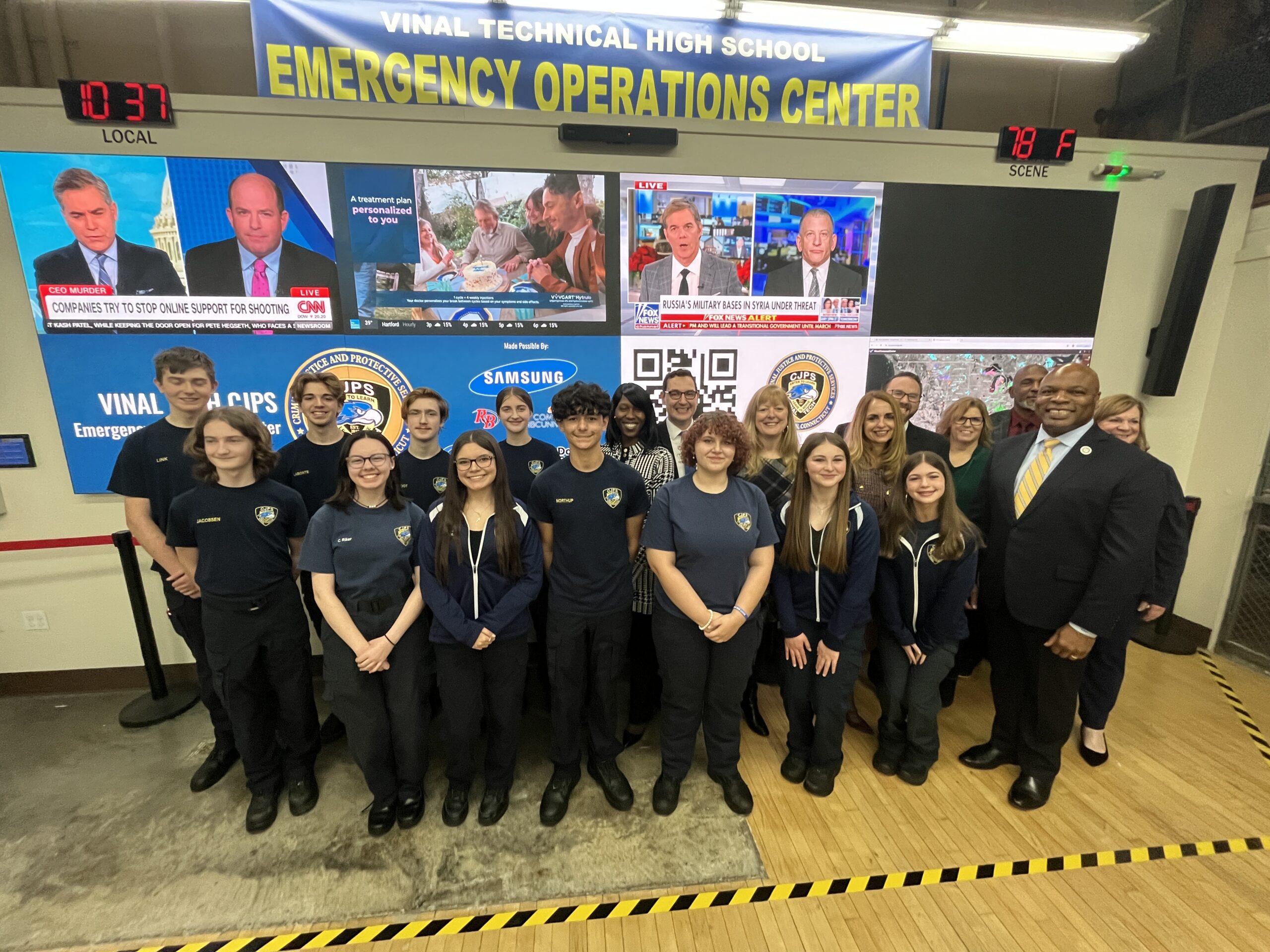 Criminal Justice and Protective Services students stand in front of a new Emergency Operations Center TV screen with CTECS and State of CT leadership;