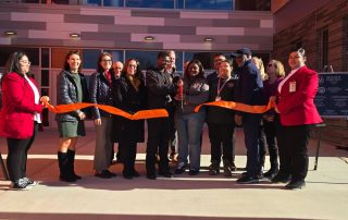 Students and dignitaries stand in front of the doors to new bullard-Havens Tech and cut the ribbon at the ribbon cutting ceremony