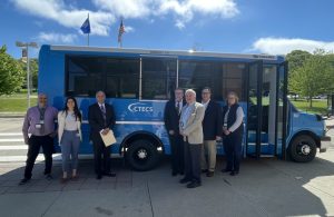 CTECS staff a state officials state outside a new electric student transport vehicle at Norwich Tech.